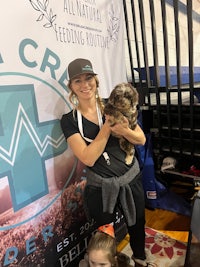 a woman holding a dog in front of a banner