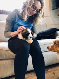 a woman petting a puppy on a couch