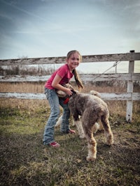 a little girl petting a dog in a field