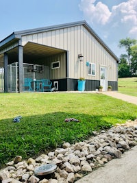 a dog kennel with a grassy area in front of it