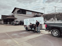 two people standing in front of a truck with a trailer