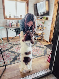 a woman is holding a dog in front of a door