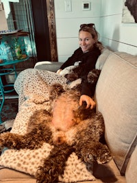 a woman laying on a couch with a dog