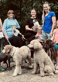 a group of people posing with their dogs in the woods